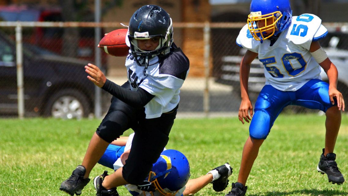 Young american football player running back breaking away from an attempted tackle. All logos and trademarks from uniforms, helmets and cleats have been removed in Photoshop