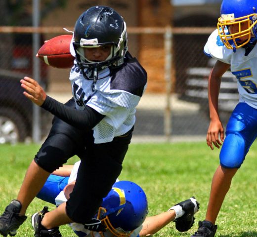 Young american football player running back breaking away from an attempted tackle. All logos and trademarks from uniforms, helmets and cleats have been removed in Photoshop